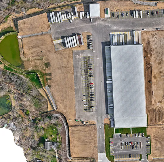 Aerial photo of factory with cars and semi trucks parked nearby.