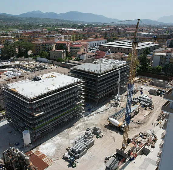 Aerial photo of construction site with 2 buildings and crane.