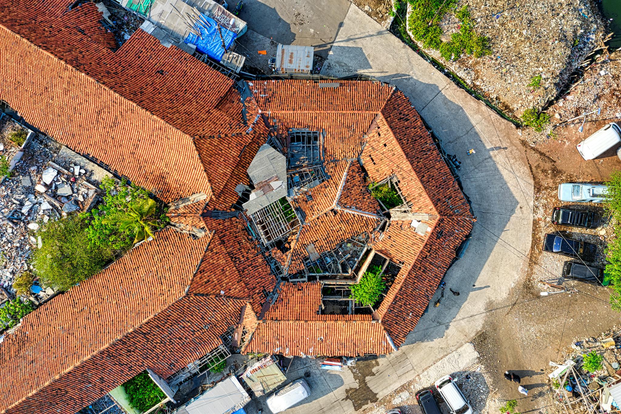 Aerial drone shot capturing a rooftop in Jakarta, showcasing unique architectural design with fallen debris around.