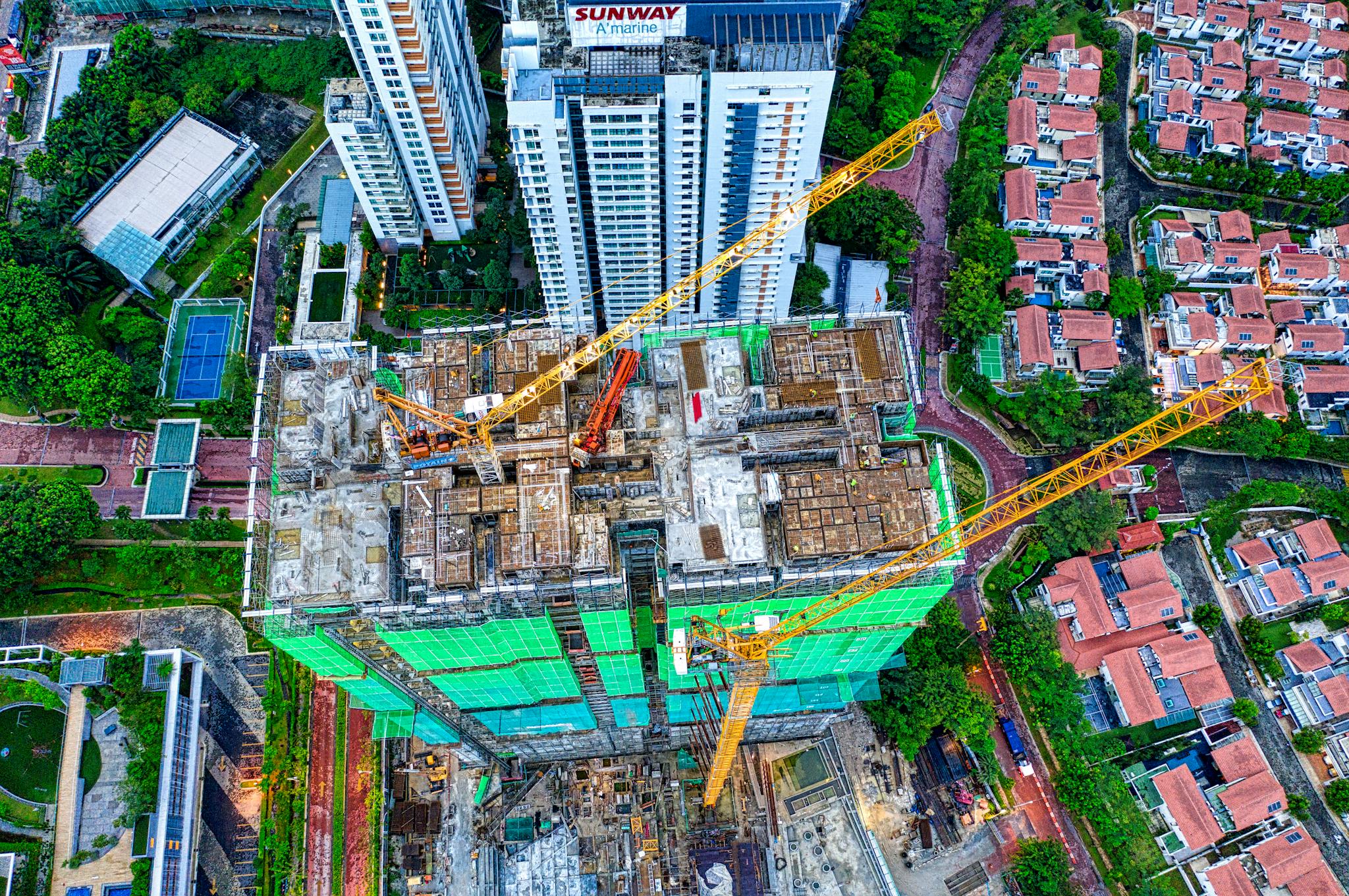 Aerial shot of a skyscraper under construction in Petaling Jaya, featuring cranes and urban landscape.